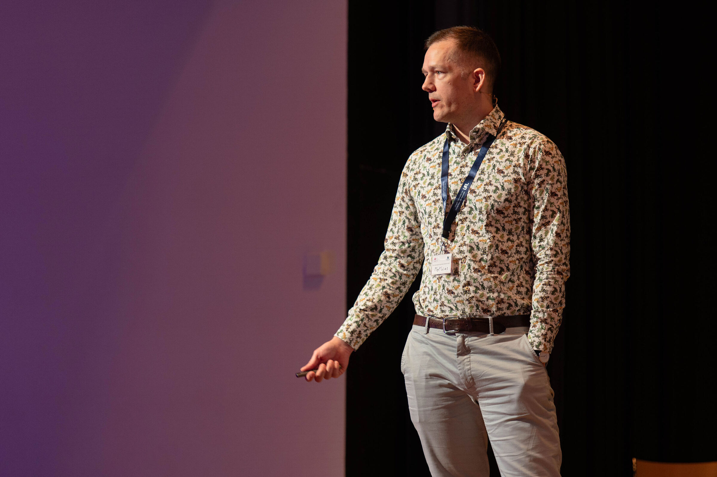 Mathias on stage at the Last Aid Conference 2026, in front of a purple lit wall